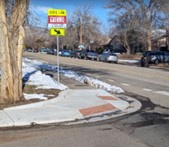 curb ramp at sidewalk corner with pedestrian crossing sign next to it